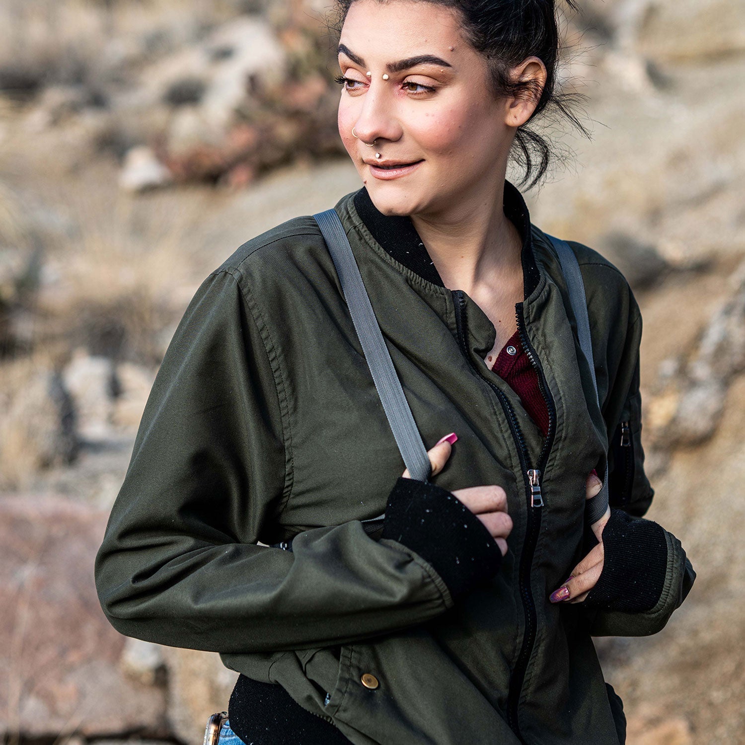 a woman in a green jacket is holding a camera